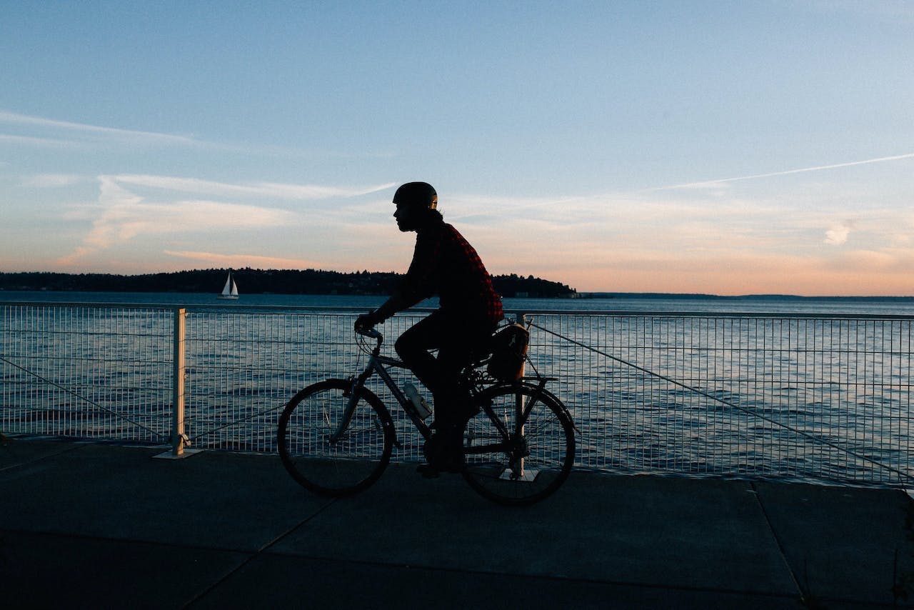 man riding his bike on a path along the waterfront