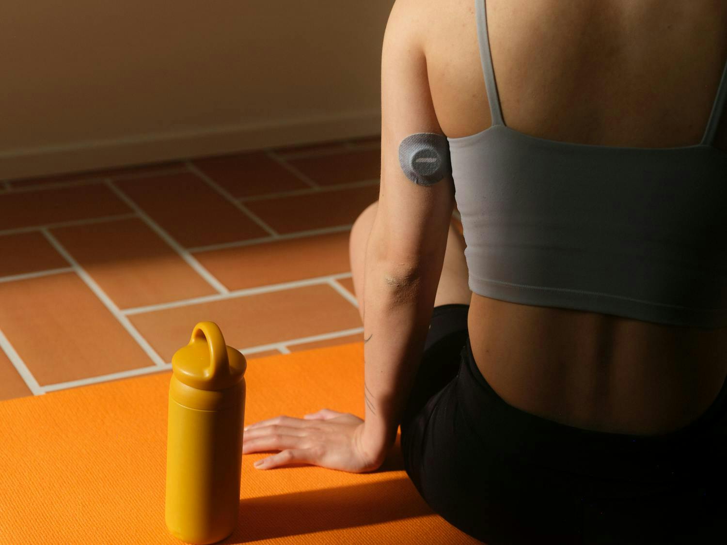 woman wearing continuous glucose monitor doing yoga